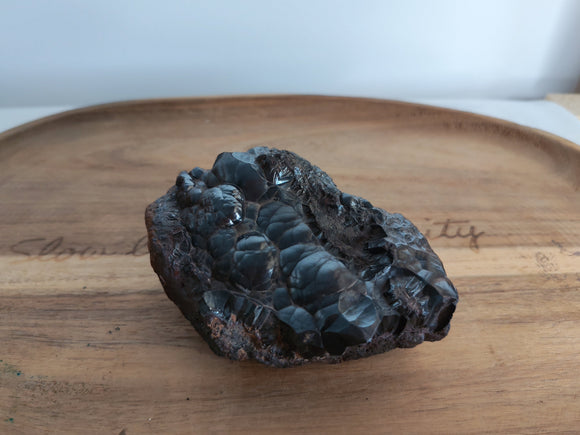 Hématite brute botryoïdale - vue de dessus sur plateau bois, bulles métalliques noires