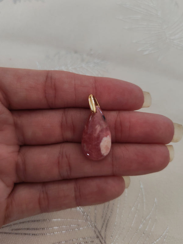 Pendentif larme rhodochrosite tenu en main - teintes rose bordeaux