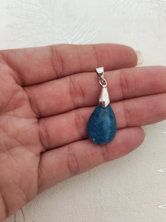 Pendentif apatite bleue - tenu en main fond tissu blanc
