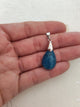 Pendentif apatite bleue - tenu en main fond tissu blanc