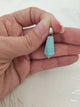 Pendentif pointe amazonite - tenu en main fond tissu blanc