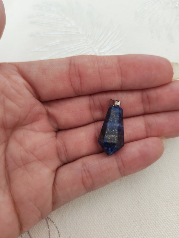 Pendentif pointe lapis lazuli tenu en main - bleu nuit reflets dorés