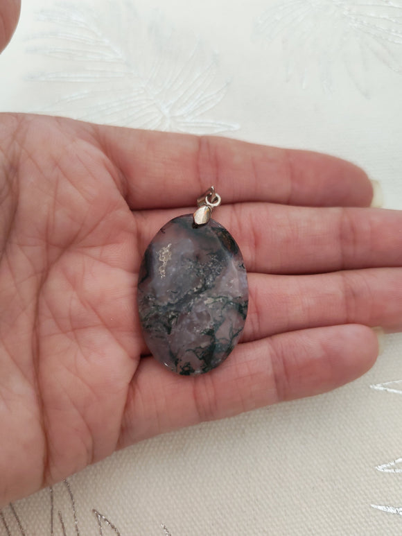 Pendentif agate mousse - tenu en main fond tissu blanc