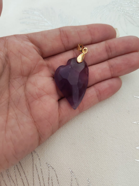 Pendentif cœur améthyste - tenu en main fond tissu blanc