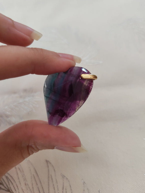 Pendentif cœur fluorite multicolore tenu en main - bandes violet bleu vert