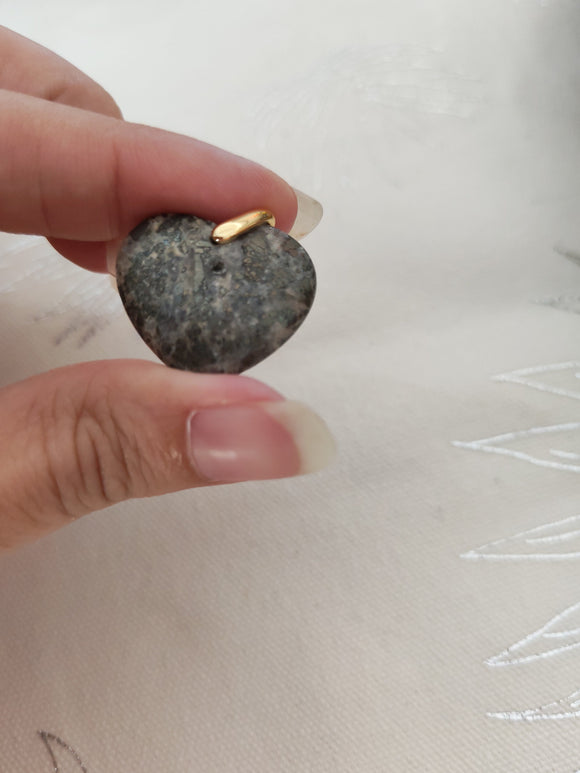 Pendentif cœur pyrite tenu en main - reflets dorés métalliques