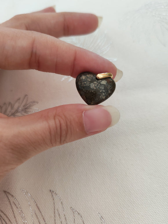 Pendentif mini cœur pyrite tenu en main - fond tissu blanc