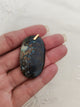Pendentif shattuckite - tenu en main fond tissu blanc