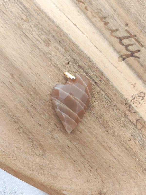 Pendentif cœur pierre de soleil - posé sur bois