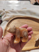 Lapin sculpté en aragonite beige-crème tenu en main vue de face